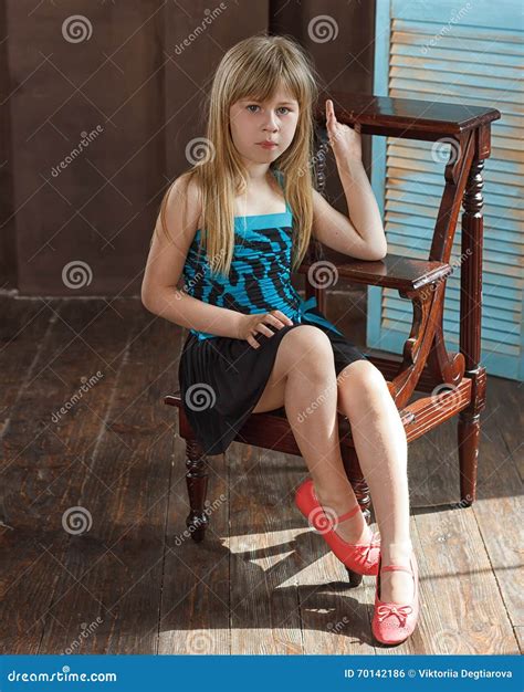 Das Mädchen 6 Jahre Alt Im Kleid Sitzt Auf Einem Stuhl Stockfoto Bild Von Entzückend Mode