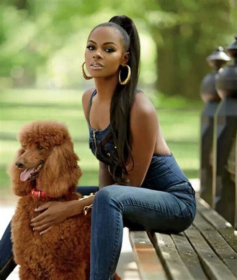 A Woman Is Sitting On A Bench With Her Poodle And Looks At The Camera