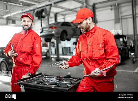 Portrait Of A Two Handsome Auto Mechanics In Red Uniform Standing With