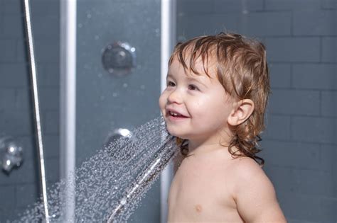 Милый ребенок играющий в ванной ребенок принимает душ портрет
