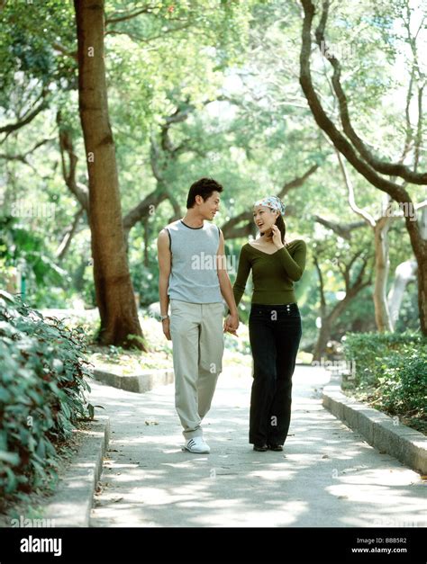 Young Couple Walking Down Path Holding Hands Nature In Background