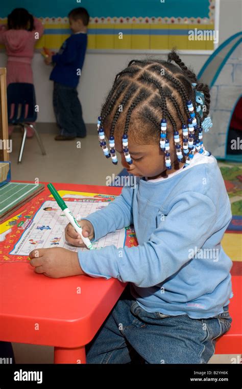 4 Year Old African American Girl Writing The Alphabet At A Table In Her