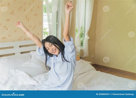 Asian Girl Wakes Up Stretches Her Arms In A White Bed In The Bedroom