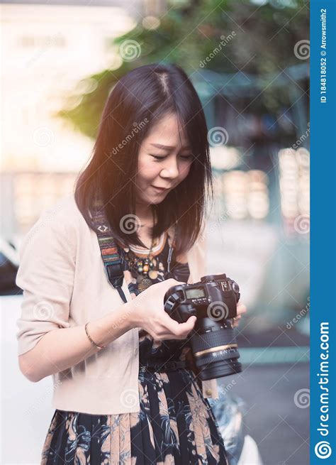 Portrait Of Asian Woman Holding And Looking Dslr Camera Stock Photo
