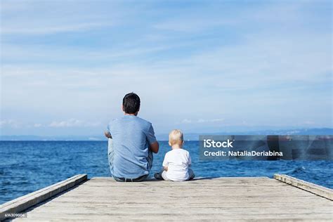 photo libre de droit de père avec fils fils assis sur le quai de la mer