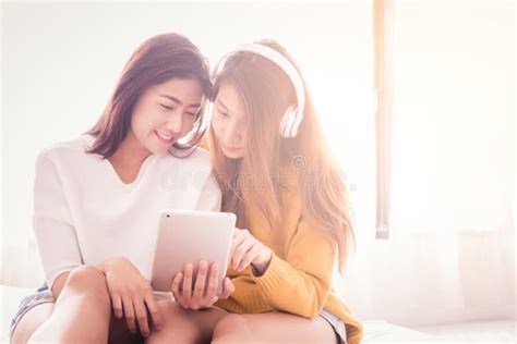 Couple Of Young Asian Women Using Tablet On White Bed With Happiness