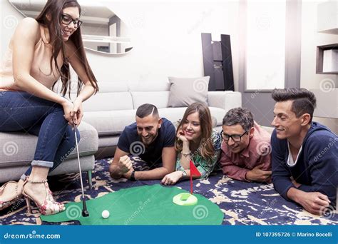 Group Of Young Adults Have Fun Playing Golf In The Living Room Stock