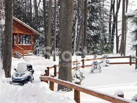 Snow Covered Cabin In The Woods With Snowmobile Stock