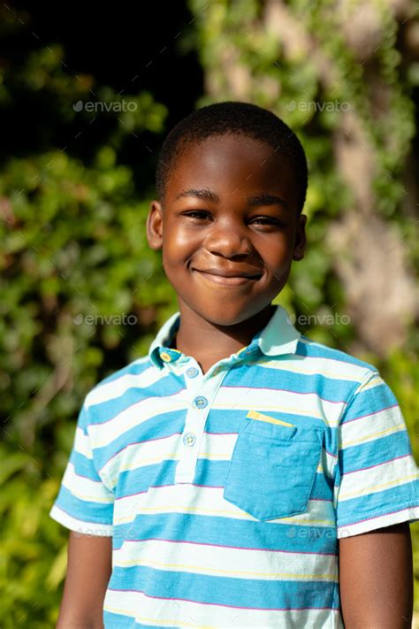 Portrait Of Cute Smiling African American Boy Standing Against Plants