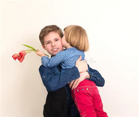 Niña Pequeña Con Flores Besando A Su Hermano Mayor El Adolescente