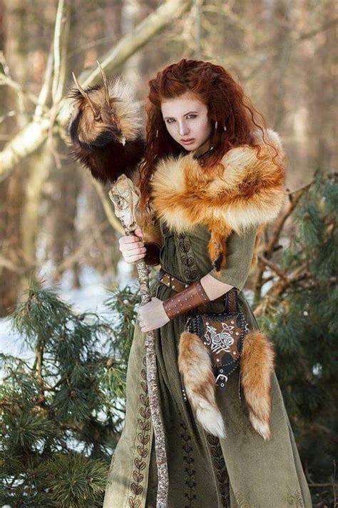 A Woman With Red Hair Is Dressed In Green And Holding A Large Cat On
