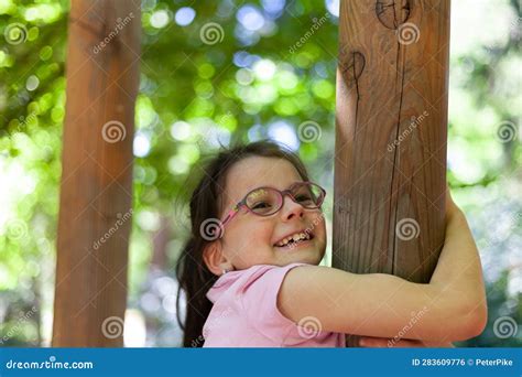 Cute Little Girl Climbing On A Tree In The Park On A Sunny Day Stock