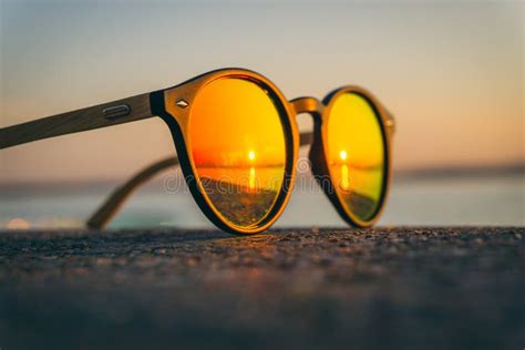 Pair Of Sunglasses On The Beach With The Reflection Of The Sunset Stock