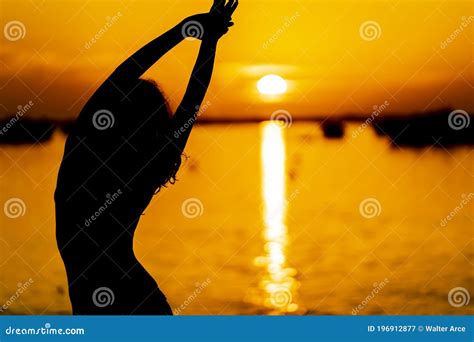 A Lovely Latin Model Is Silhouetted As She Poses With The Rising Sun Behind Her On A Romantic