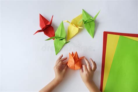 Children`s Hands Do Origami From Colored Paper On White Background