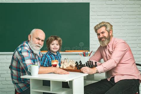 Grandfather Father And Child Son Playing Chess Learning At Home