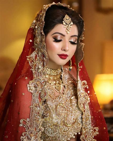 a woman in a red and gold bridal outfit with her eyes closed looking at the camera