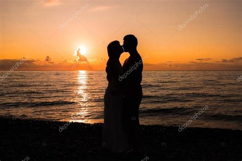 Two Young Lovers Standing On A Beach And Looking To Each Other Stock