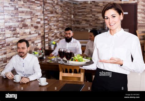 Beautiful Female Waiter Welcoming Guests To Country Restaurant Stock