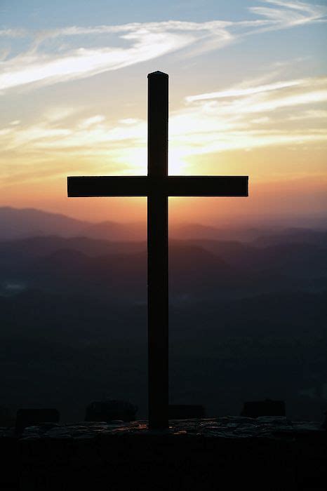 A Cross On Top Of A Hill At Sunset