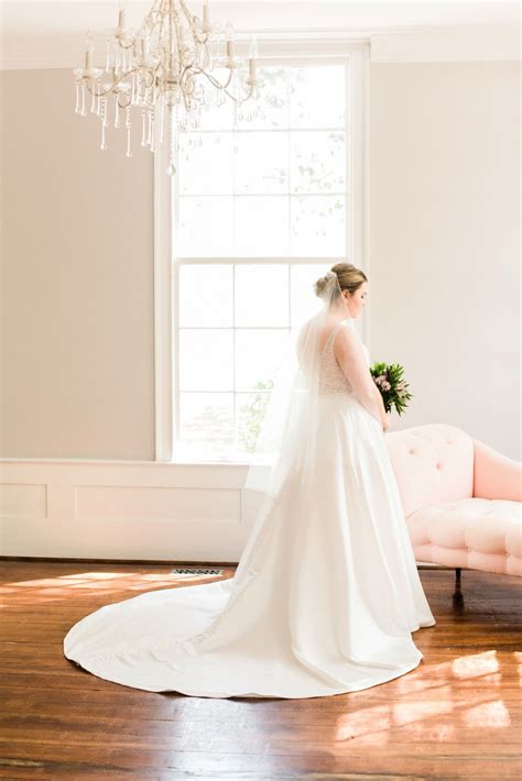 Bride In A Sleeveless Gown With A Veil Standing Inside Next To A Light