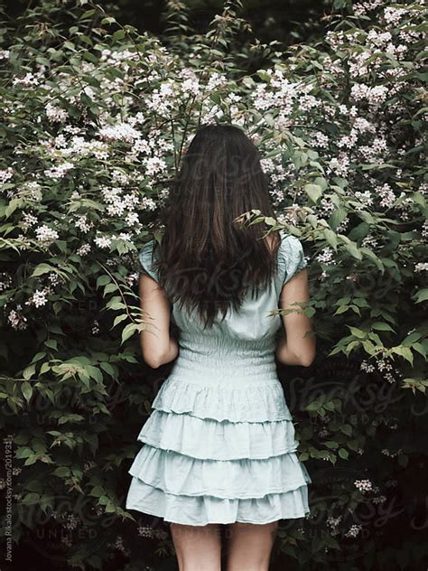 Back View Of A Young Woman Standing In Front Of A Bush By Jovana Rikalo