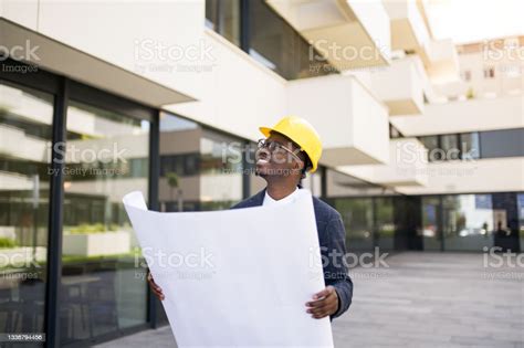 Young Architect Examining A Blueprint In Front Of An Office Building