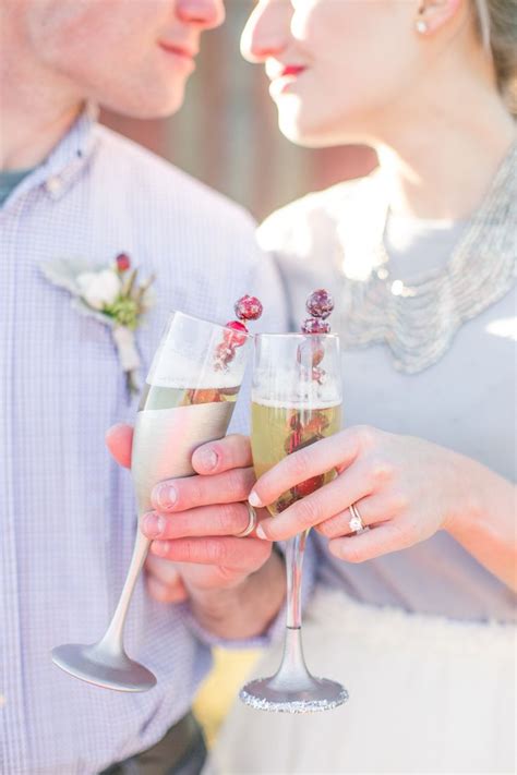 A Man And Woman Holding Wine Glasses With Flowers On Them