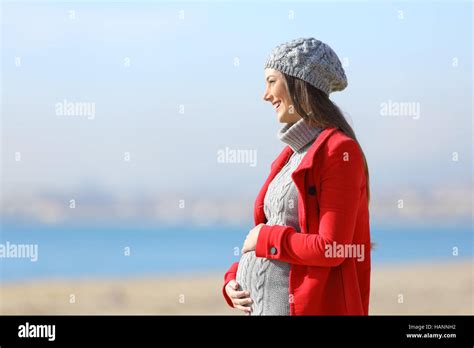 side view portrait of a happy pregnant woman taking a walk on the beach in a sunny winter day
