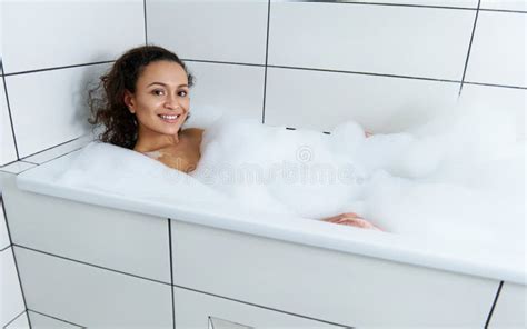 Portrait Of Seductive Young Smiling Latin American Woman Taking Relaxing Bath With Foam Stock