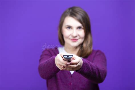 Caucasian Female In Purple Clothing Holding And Pointing Tv Remote