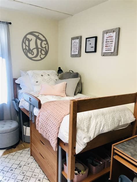 A Bedroom With A Bed Desk And Chair In It Next To A Wall Mounted Monogram
