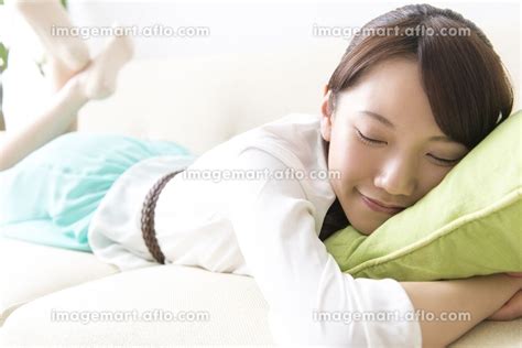 ソファで寝転ぶ女性の写真素材 24022351 イメージマート