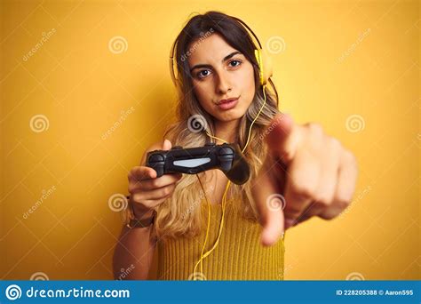 Young Beautiful Woman Playing Video Game Using Gamepad Over Yellow