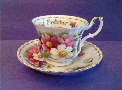 A Tea Cup And Saucer With Flowers Painted On The Side Sitting On A