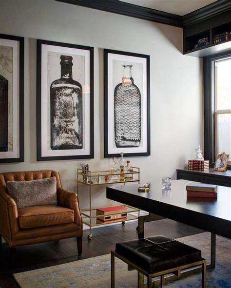A Glass And Gold Bar Cart Brown Leather Armchair And Oversized Artwork