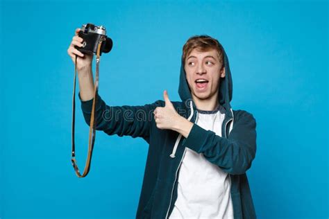 Portrait Of Young Man In Casual Clothes Doing Selfie Shot On Retro Vintage Photo Camera Showing