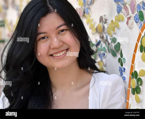 pretty southeast asian girl with beautiful long hair smiles for the camera at bangkok s wat arun