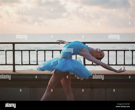 Dancing Ballerina In Blue Ballet Tutu And Point On Embankment Above