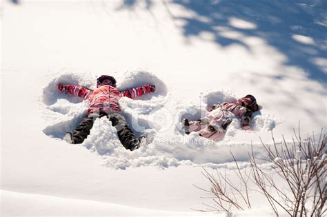 Two Young Girls Doing Snow Angels Full Length Horizontal Stock Photo