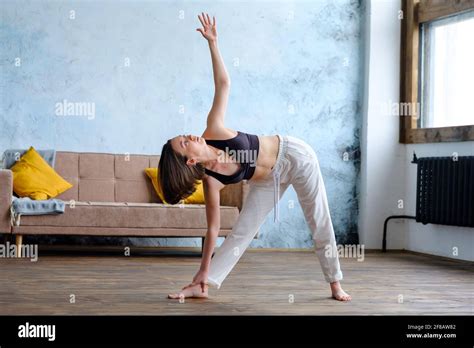 Calm Young Woman Brunette In White Does Utthita Trikonasana Practicing