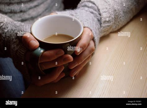 Woman Holds Hot Cup Of Tea Or Coffee Warming Her Hands Sat At A