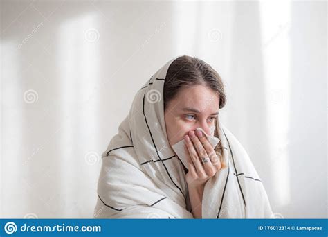 Ill Woman Under White Blanket Blowing Her Nose On White Background