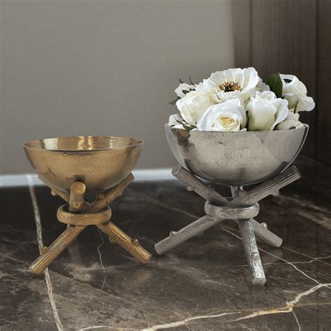 Two Metal Bowls With Flowers In Them Sitting On A Marble Counter Top