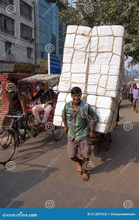 Indian Man Pulling Cart With Goods In The Busy Street Of Delhi