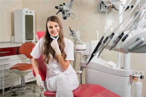 Smiling Female Doctor With Long Hair Sitting On Dental Chair And