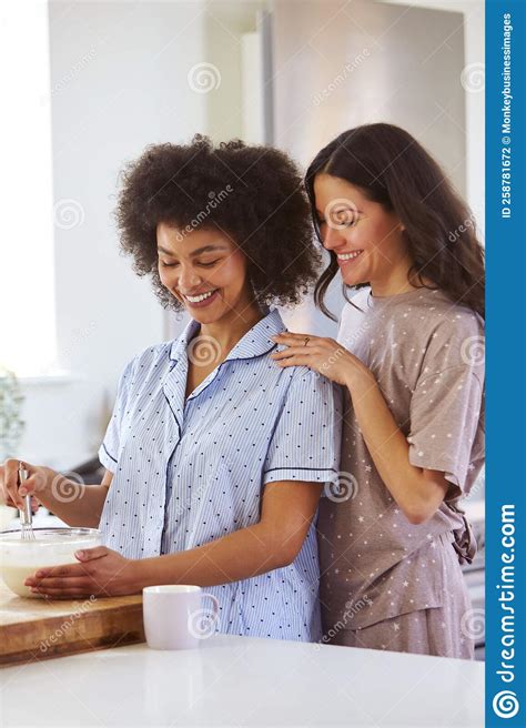 Loving Same Sex Female Couple Wearing Pyjamas Making Morning Pancakes In Kitchen At Home Stock