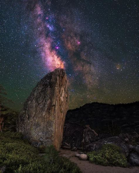 The Night Sky Is Filled With Stars Above A Large Rock In The Middle Of