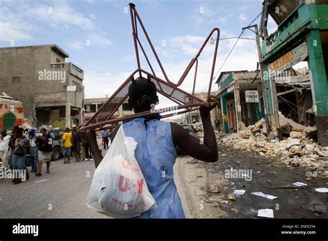 A Woman Walks Through Rubbles With A Chair Taken From A Collapsed Store