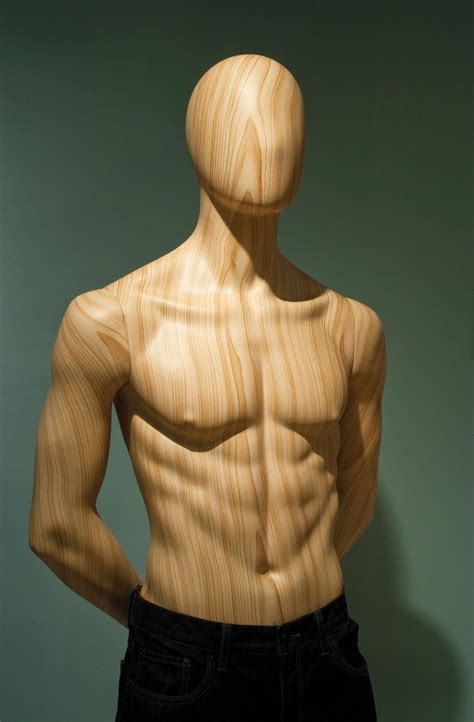 A Wooden Mannequin Standing In Front Of A Green Wall With His Hands On